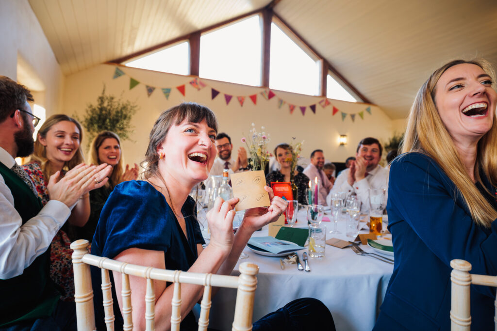 Bride reacts to grooms speech where a bridesmaid gets the question correct at launcells barton wedding venue.captured by Cornwall Wedding Photographer Chris Armstrong Photography